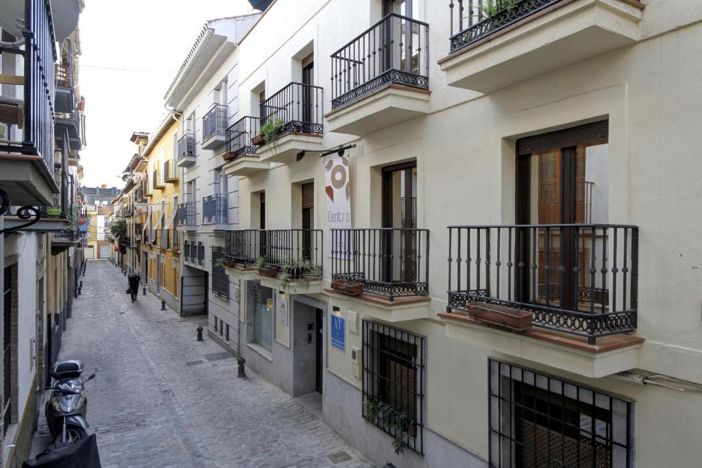 格拉纳达Apartamentos Turísticos Centro的城市的小巷,有建筑和阳台