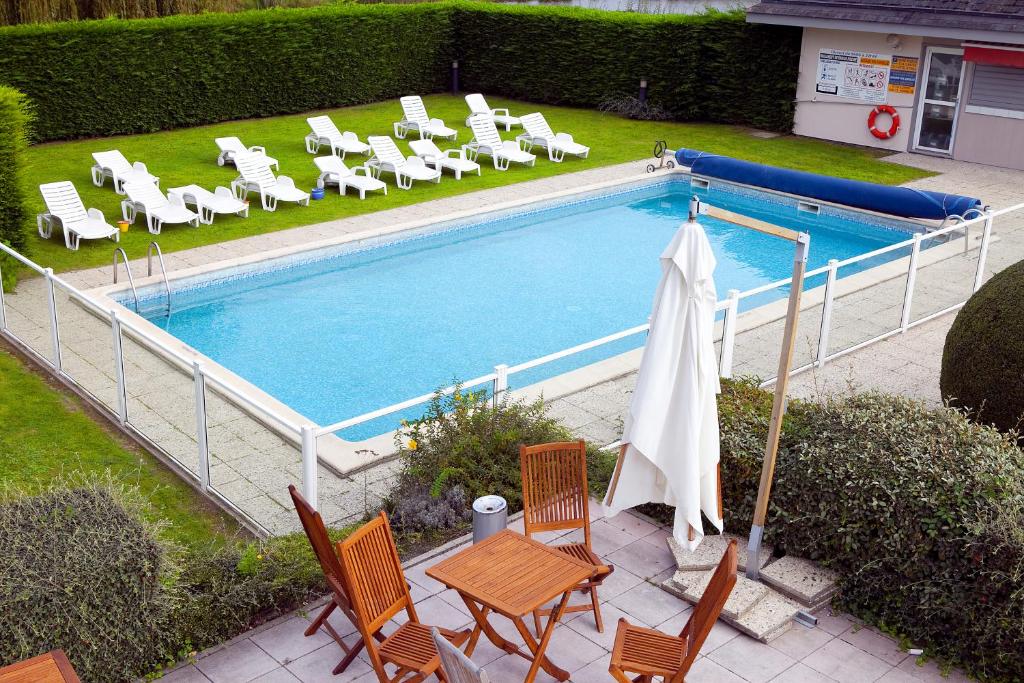 多维尔基里亚德德维勒圣阿尔努特酒店的享有带椅子和遮阳伞的游泳池的顶部景致