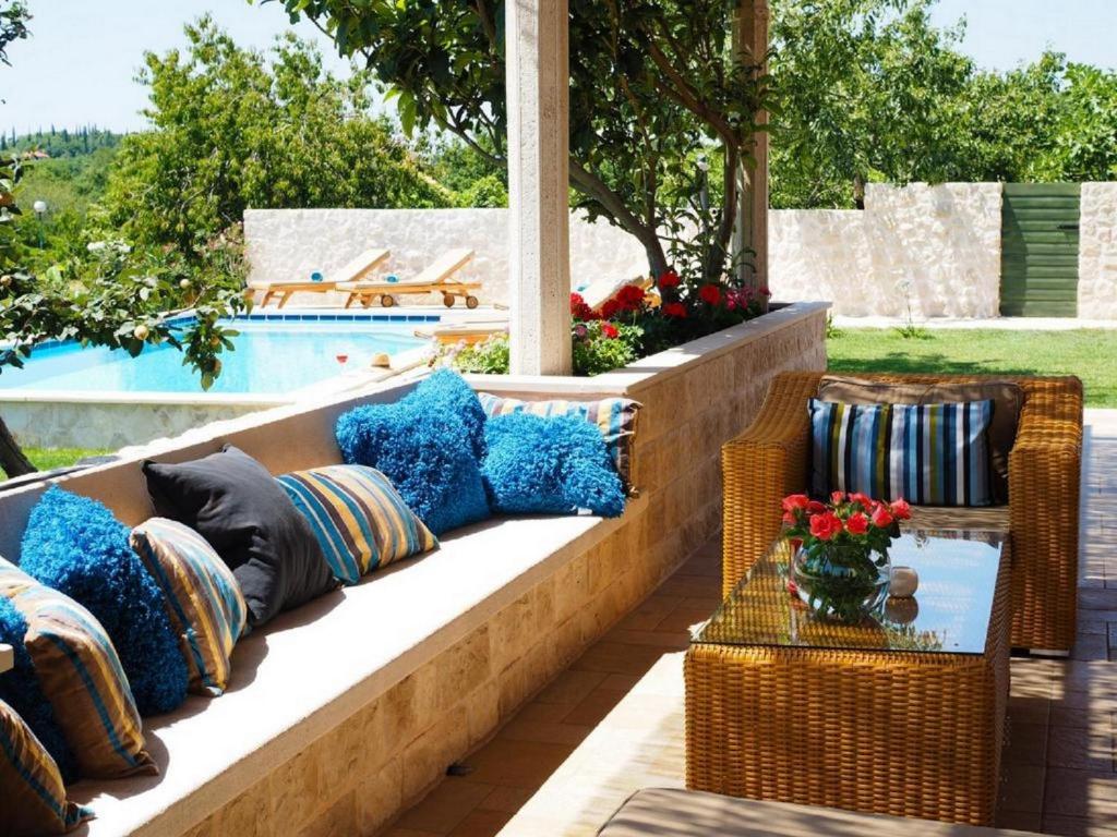 西利皮Villa Antonija的游泳池旁的长凳上配有枕头的天井