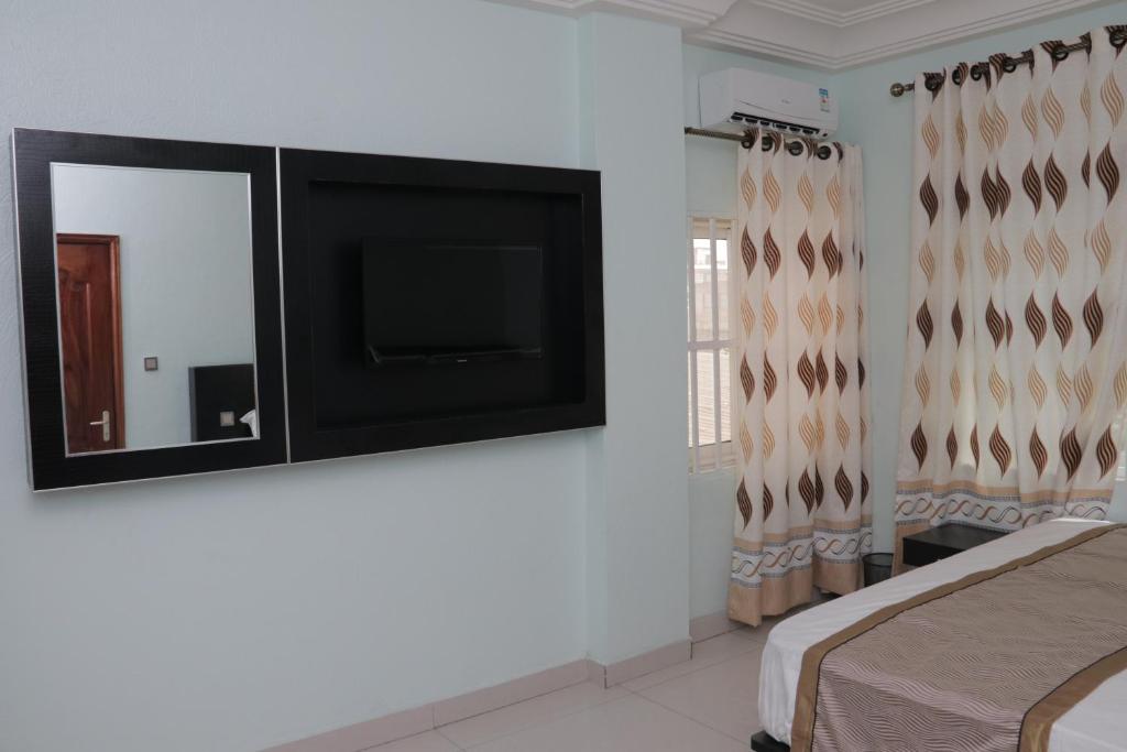 科托努BERACA INN的一间卧室设有平面电视和一张床。