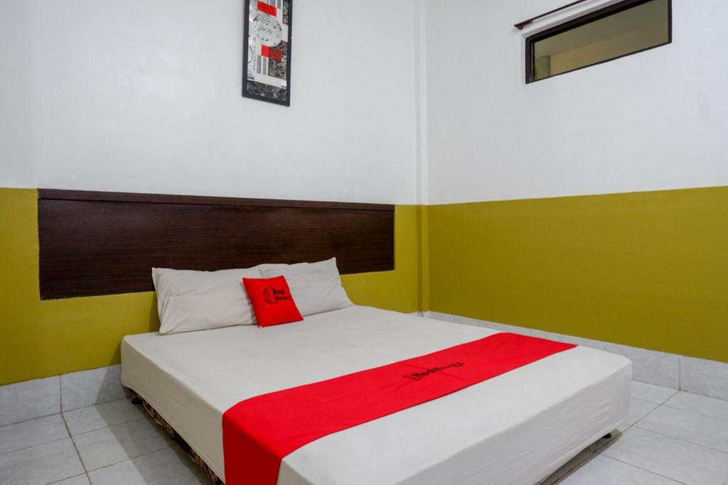 肯达利RedDoorz Syariah @ Hotel Wisma Indonesia Kendari的一间卧室配有一张床铺,床上铺有红色毯子