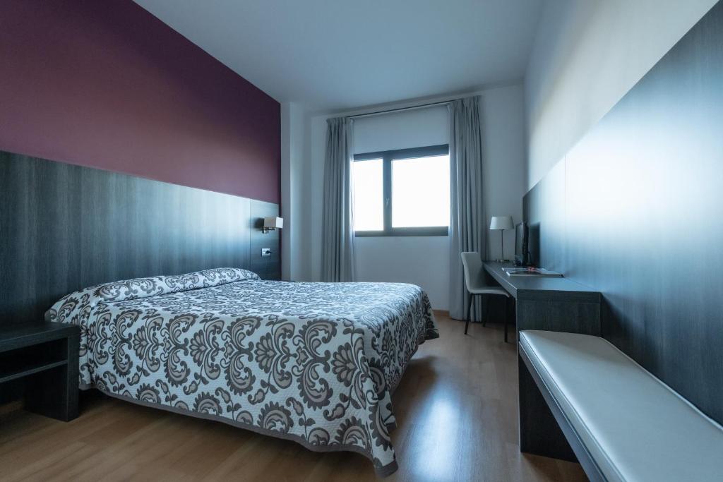米兰达德埃布罗Hotel Abades Via Norte的一间卧室配有一张床、一张书桌和一个窗户。