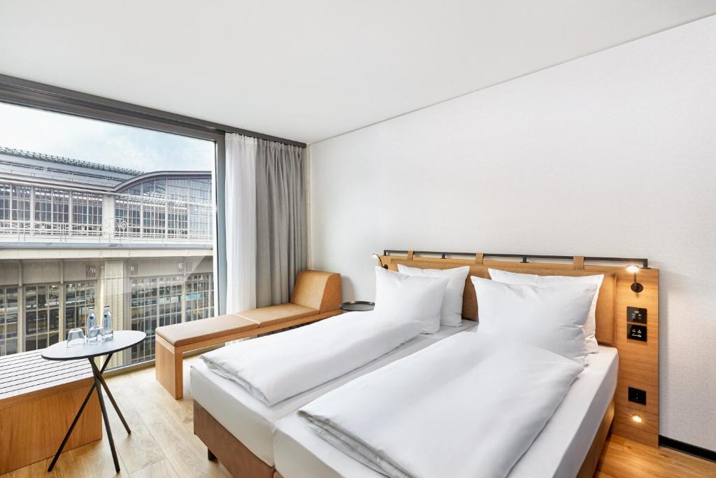 莱比锡H2 Hotel Leipzig的一间卧室设有两张床和大窗户