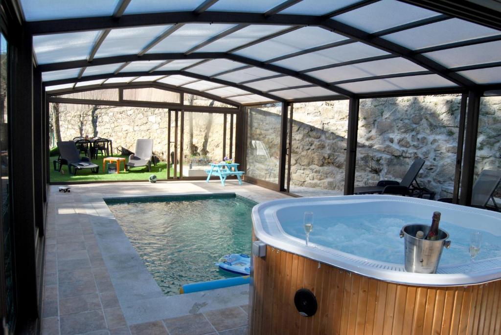 Collado MedianoCasa Rural Villa Angeles con Piscina y Jacuzzi的一座房子内带热水浴池的游泳池