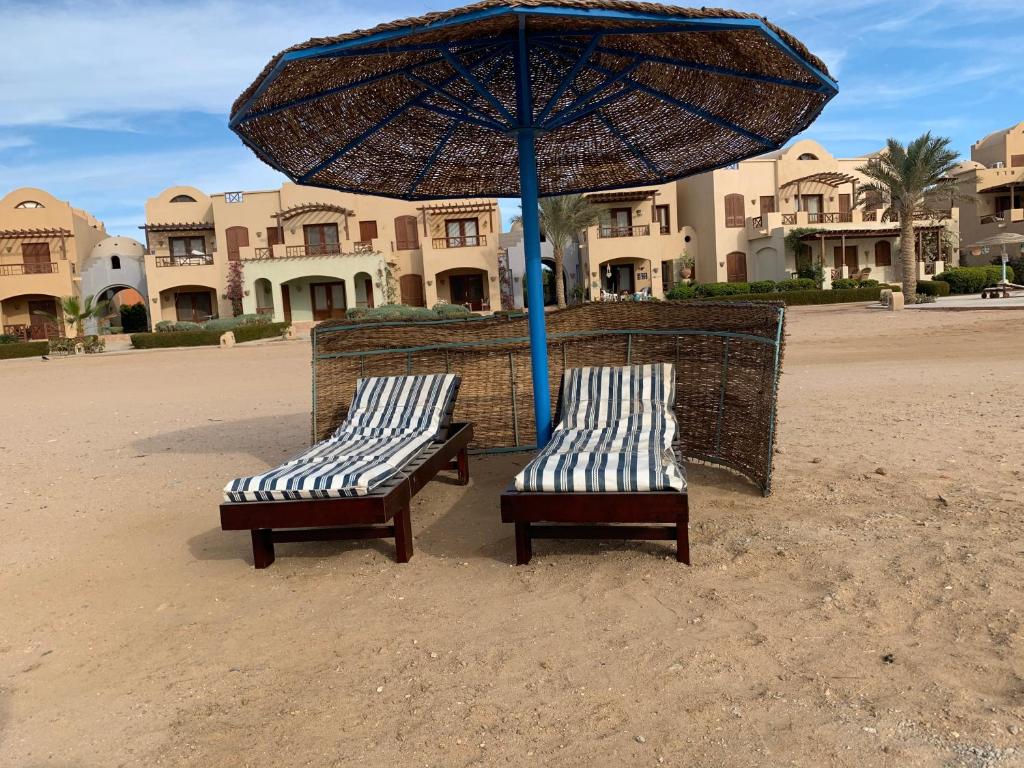 赫尔格达One-Bedroom apartment ground floor for Rent in El Gouna的海滩上两把长椅,放在伞下