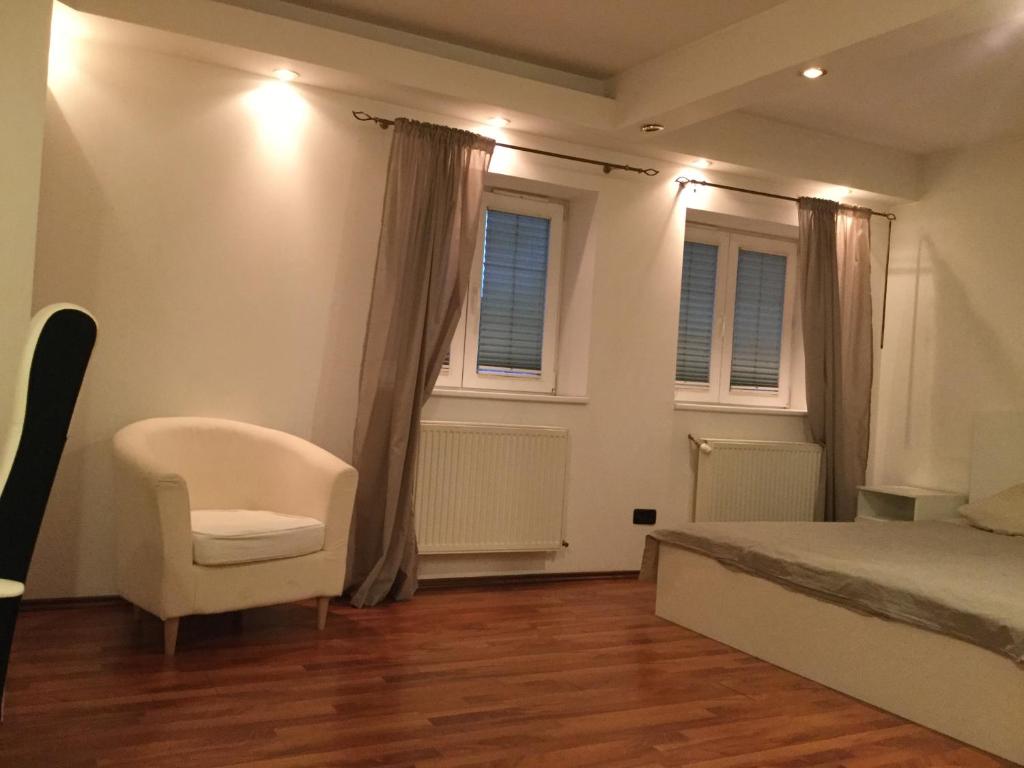 布加勒斯特Garsoniera zona baneasa的一间卧室配有一张床、一把椅子和窗户。