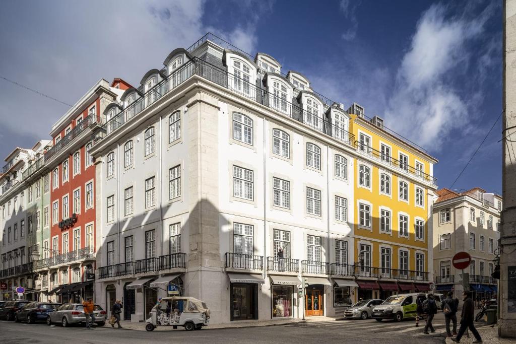 里斯本Lisbon Serviced Apartments - Madalena的一条有汽车的城市街道上白色的大建筑