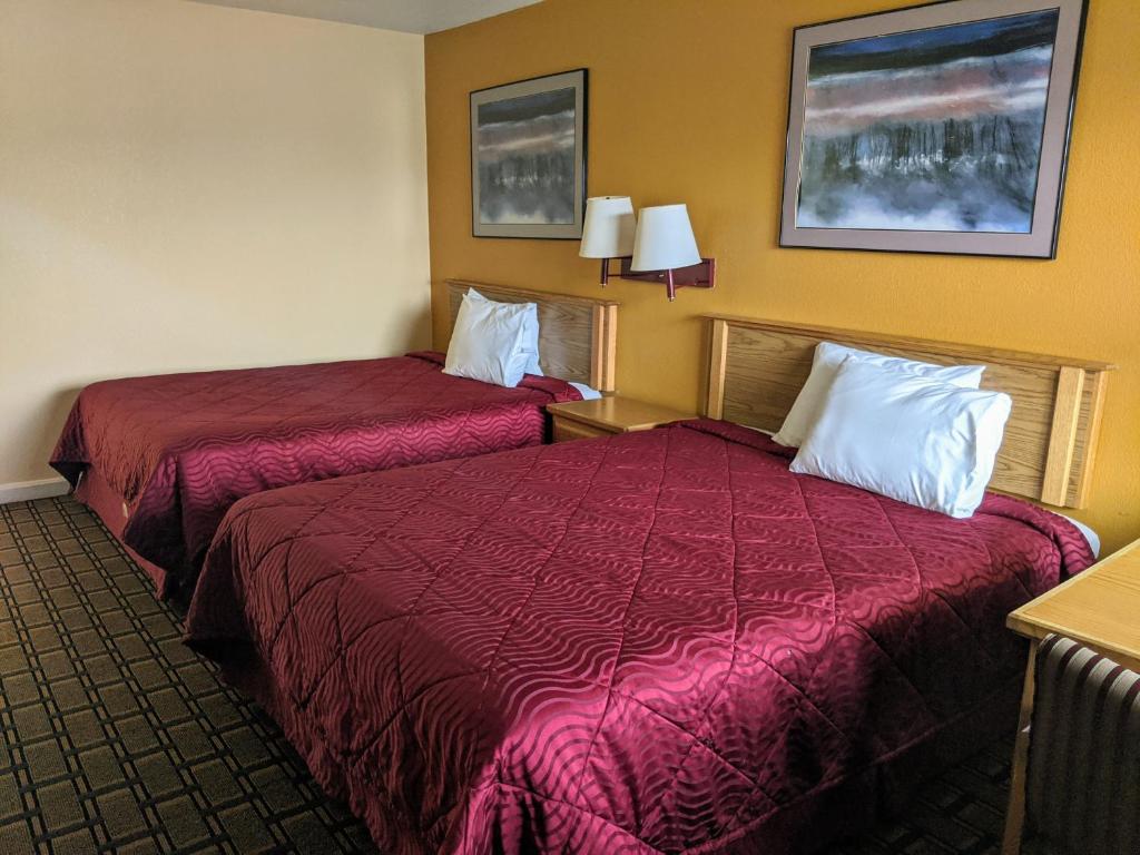 韦恩堡Executive Inn的两张位于酒店客房的床铺,配有红色床单