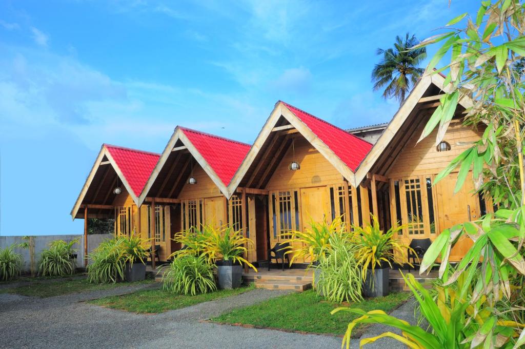 亭可马里Amazon Beach Cabana的一座木房子,拥有红色的屋顶和棕榈树