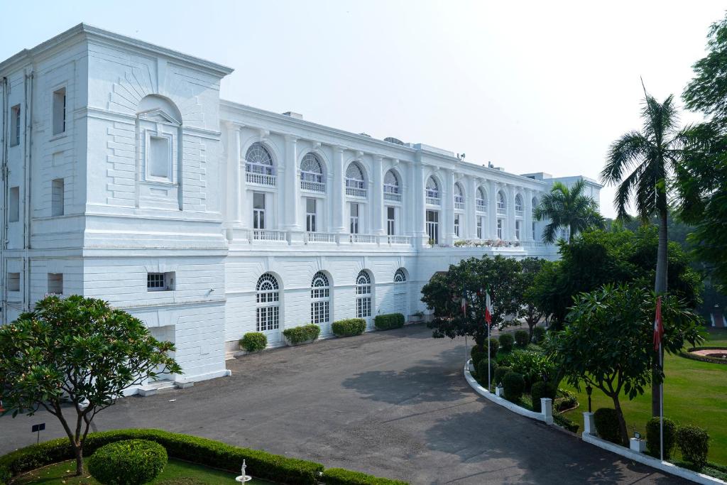 新德里新德里梅顿酒店的一座白色的大建筑,设有庭院和棕榈树