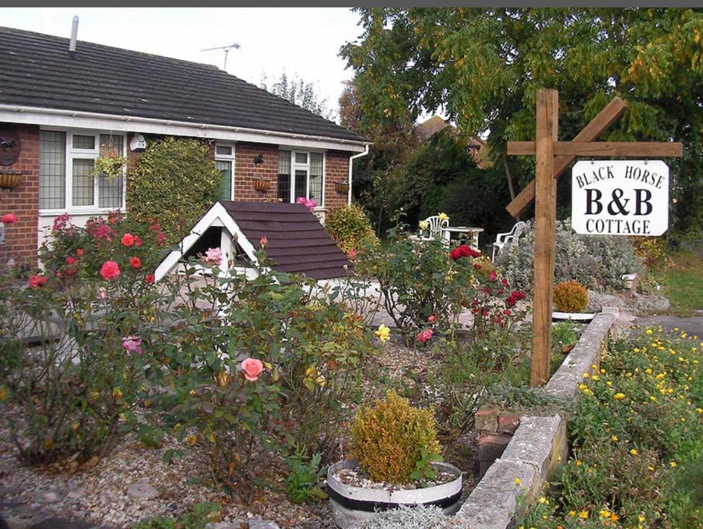 StonewoodBlack horse cottage的一座带鲜花和标志的花园的房子