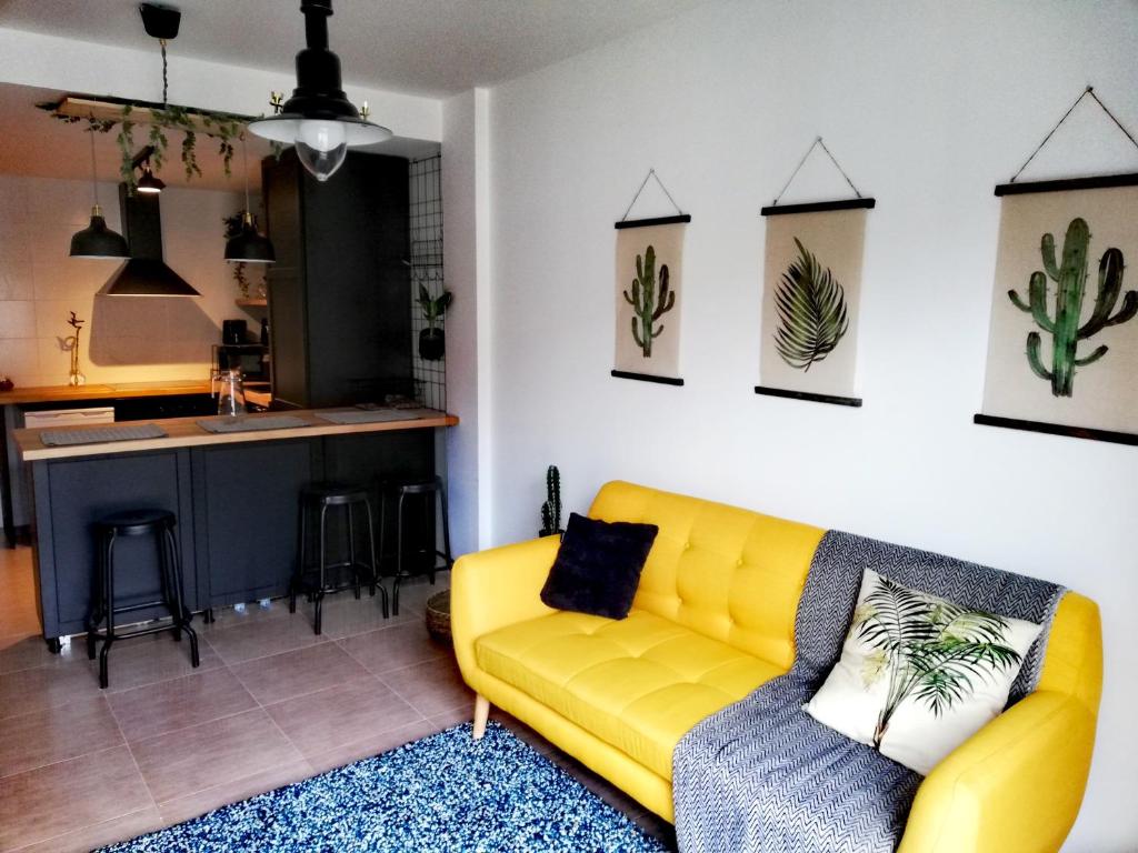 阿雷斯Pintoresco piso a 5 min de la playa wifi/Netflix的一间带黄色沙发的客厅和一间厨房