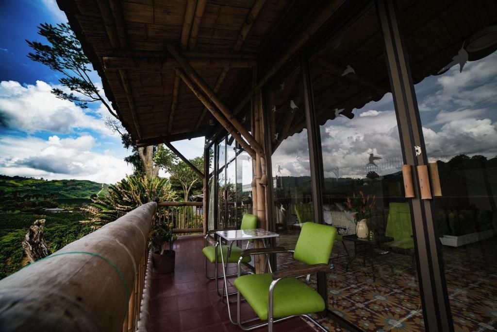 ChinchináHacienda Guayabal的阳台设有带绿色椅子和桌子的庭院