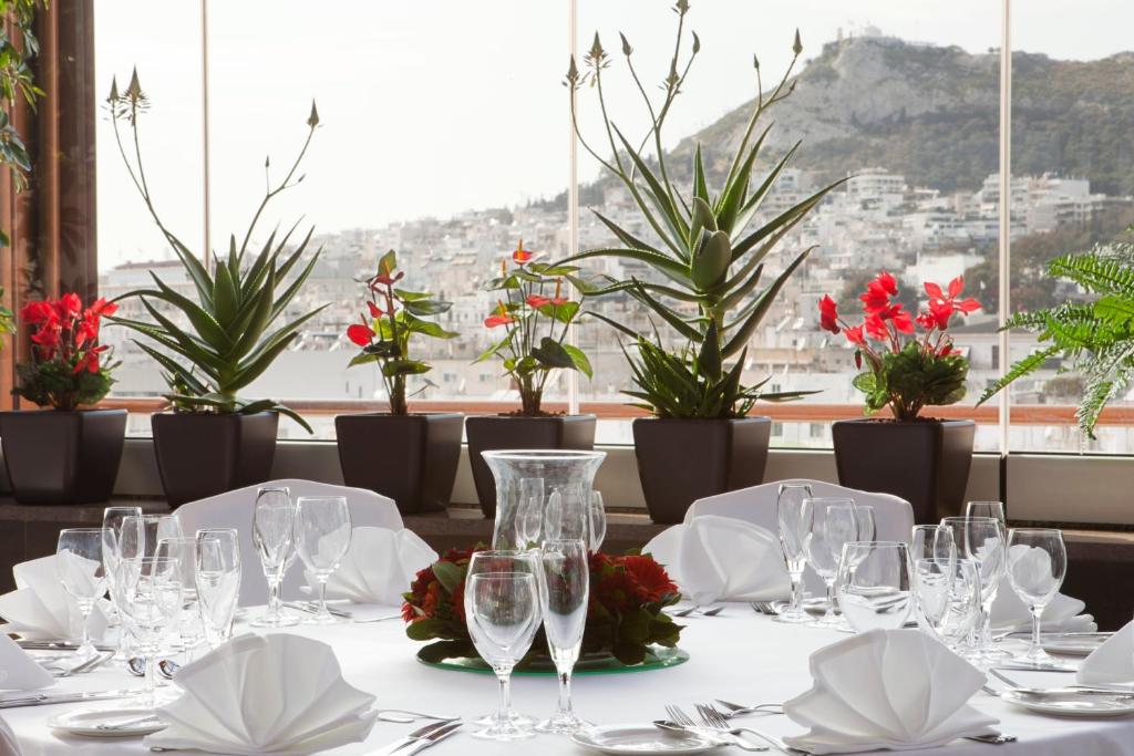雅典雅典市中心皇冠假日酒店的餐厅的桌子,有玻璃杯和鲜花