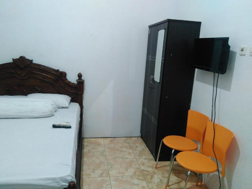 BaubauWisma Kahyangan的一间卧室配有一张床、两把椅子和一台电视