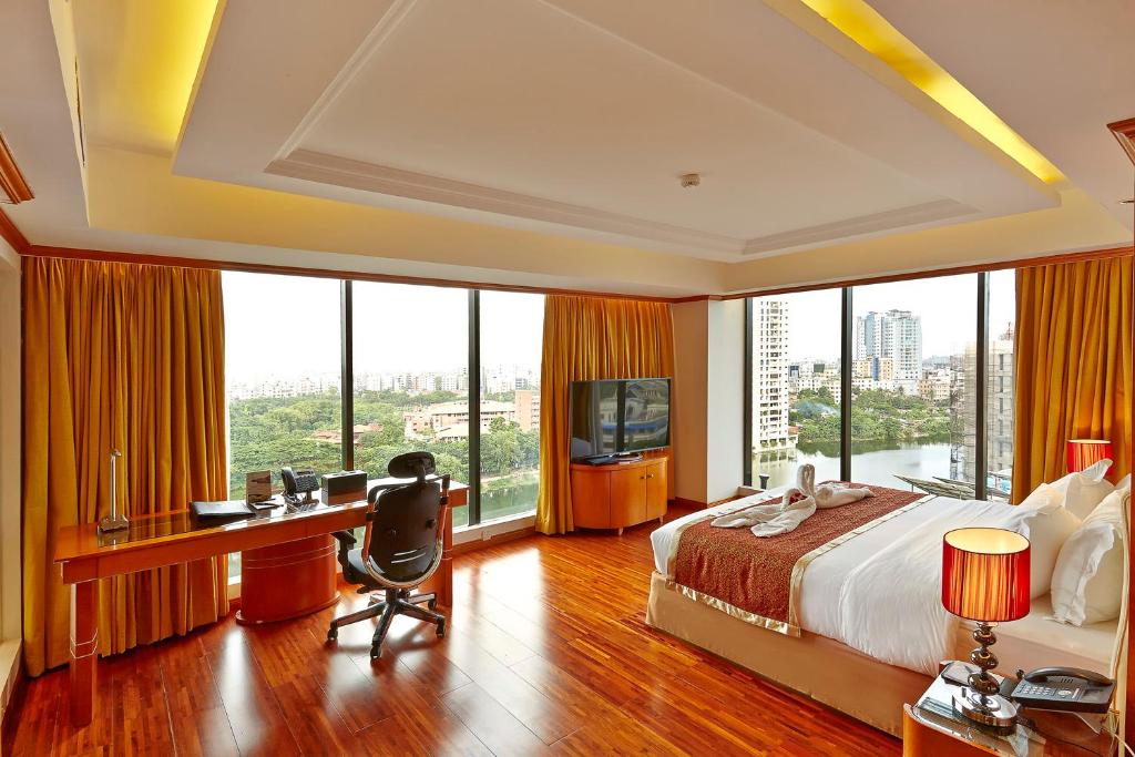 达卡六季酒店的一间卧室配有一张床和一张书桌及电视