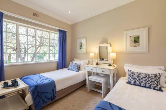 约翰内斯堡Tiree B&B的一间卧室设有两张床、一台电视和一扇窗户。