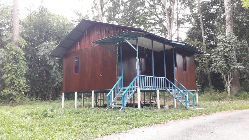 瓜拉江沙Chalet Kampong Guar, Manong的一条红色小屋,在道路前设有蓝色楼梯