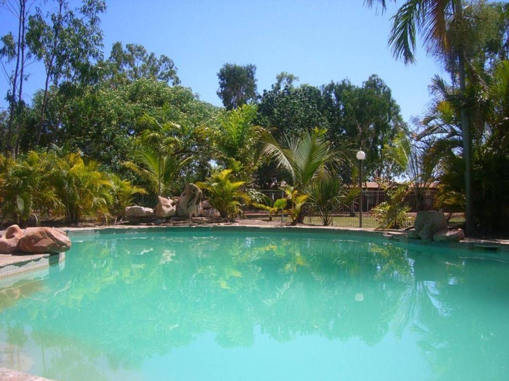 MatarankaTerritory Manor Motel & Caravan Park的一座拥有蓝色海水和树木的大型游泳池