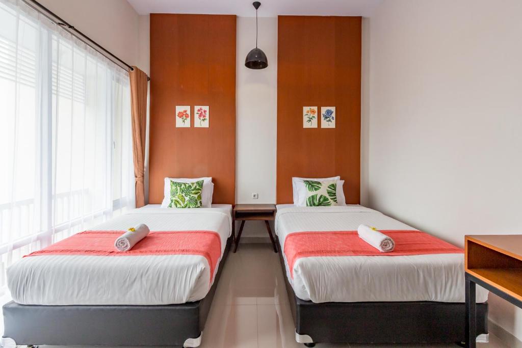 日惹Omah Manis的一间设有两张红色和白色床单的房间