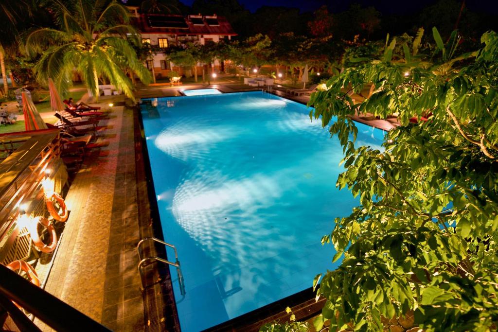 阿努拉德普勒4 U萨利亚花园酒店的棕榈树和椅子的夜间游泳池