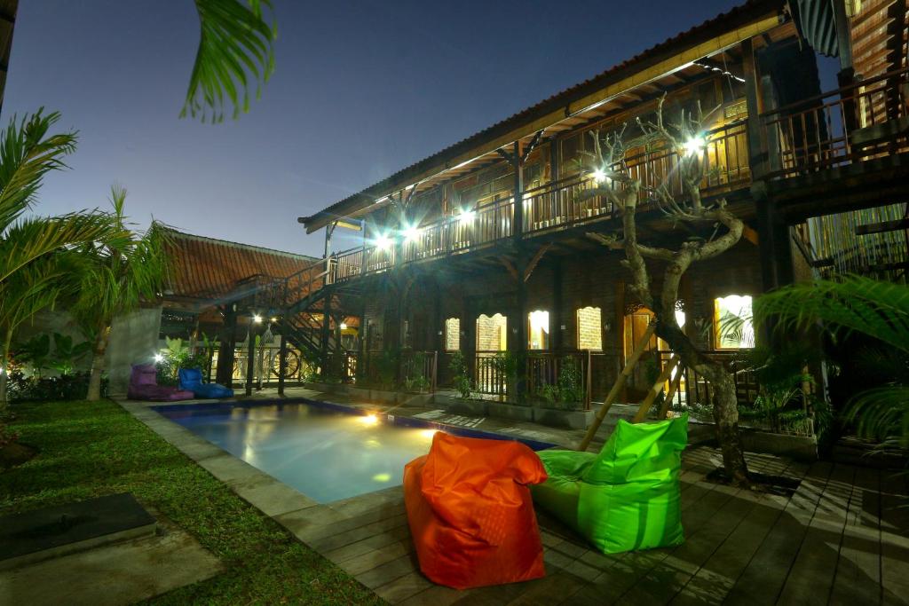 坎古Tropical Canggu Hostel的一座晚上设有游泳池的房子