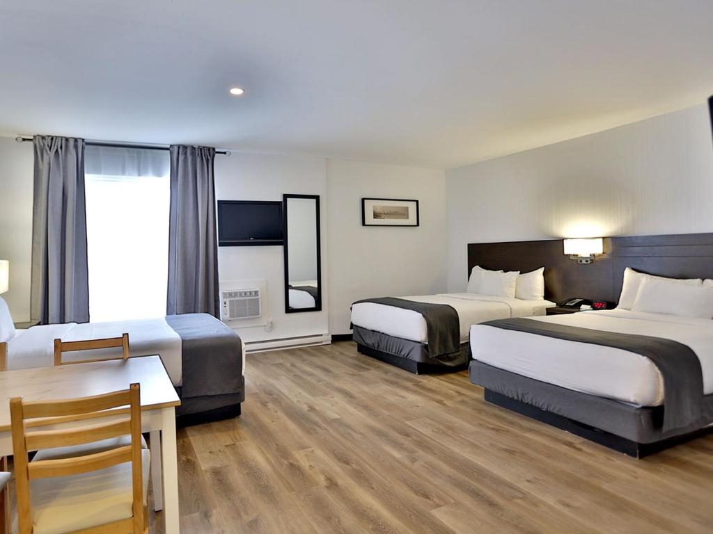 蒙特利尔Hotel Newstar Montréal的酒店客房设有两张床和一张桌子。