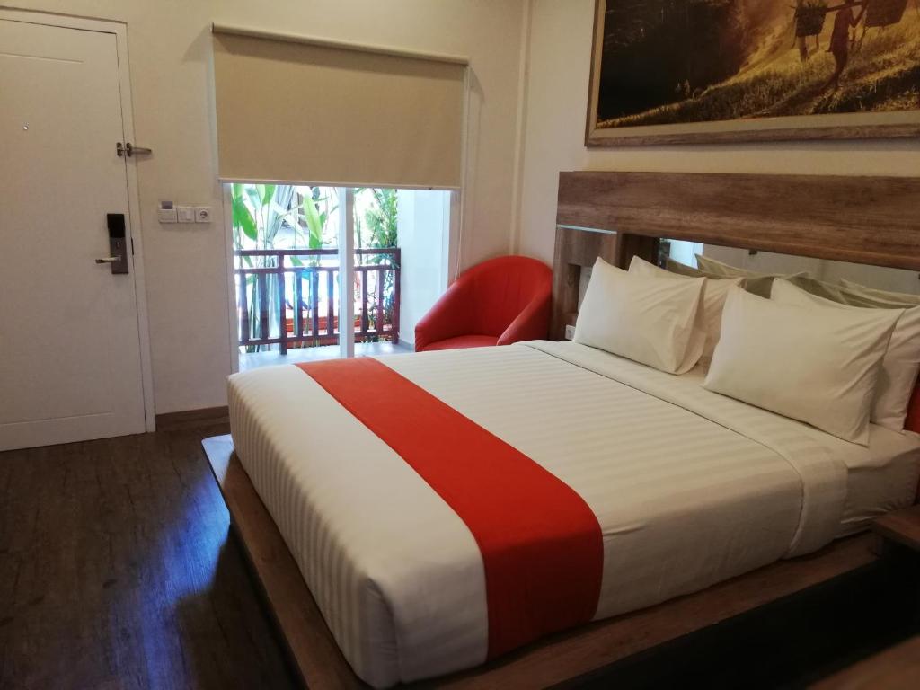 库塔The Nyaman Bali的一间卧室配有一张大床和红色椅子
