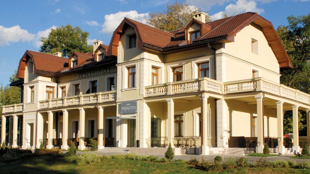 萨拉热窝赫塞哥维纳酒店的一间白色的大房子,有棕色的屋顶