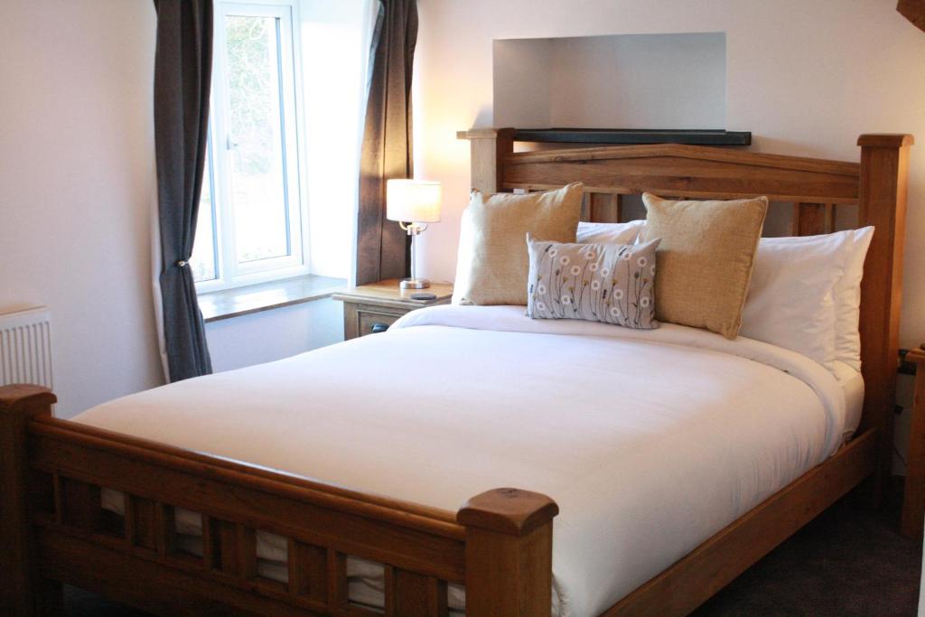 多尔顿因弗内斯The Black Dog Inn的卧室配有一张带白色床单和枕头的大床。