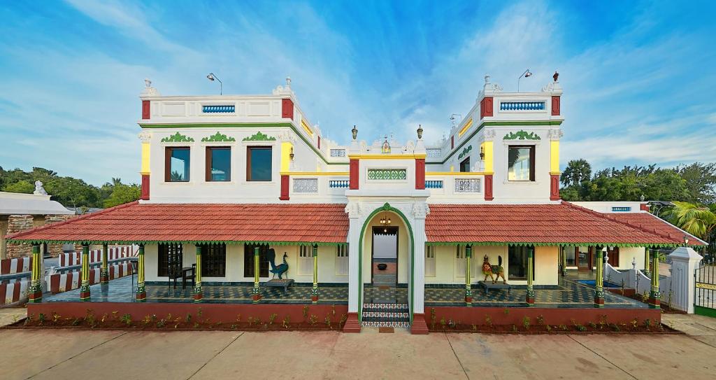马哈巴利普拉姆Marutham Village Resort的一座白色的大建筑,有红色的屋顶