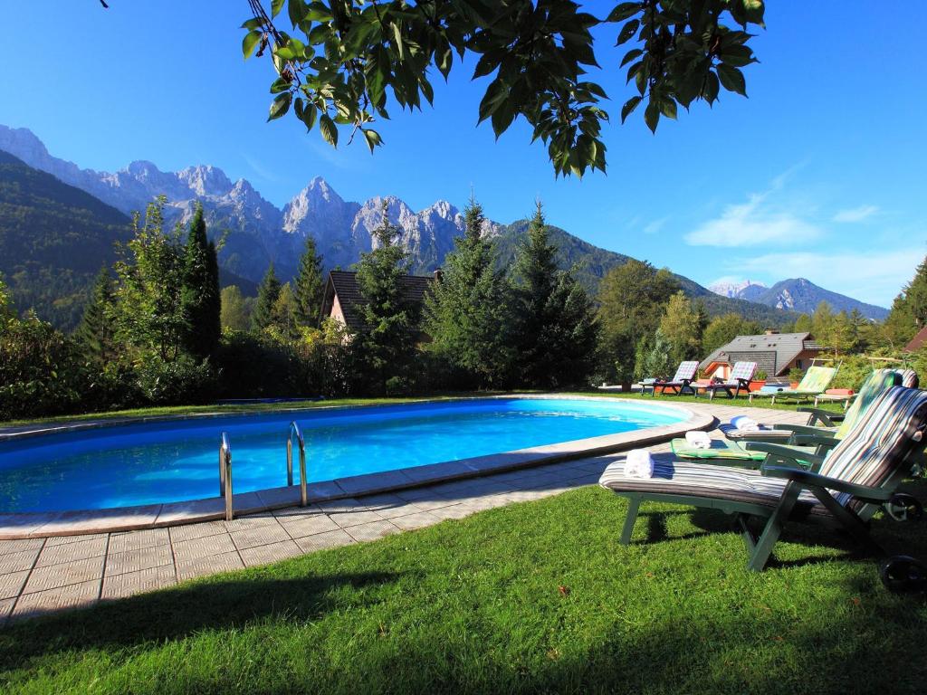 克拉尼斯卡戈拉Vila Edelweiss Rooms&App Kranjska Gora的一个带椅子的游泳池,背景是山脉