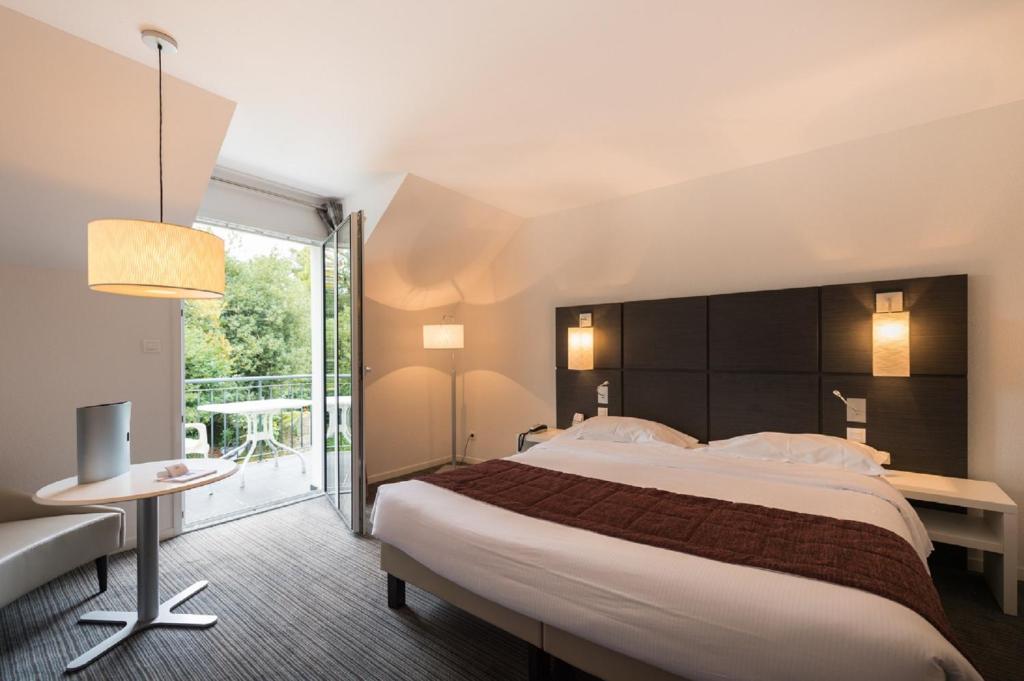 阿旺桥Résidence Goélia Le Domaine de Pont-Aven的酒店客房设有一张大床和一个阳台。