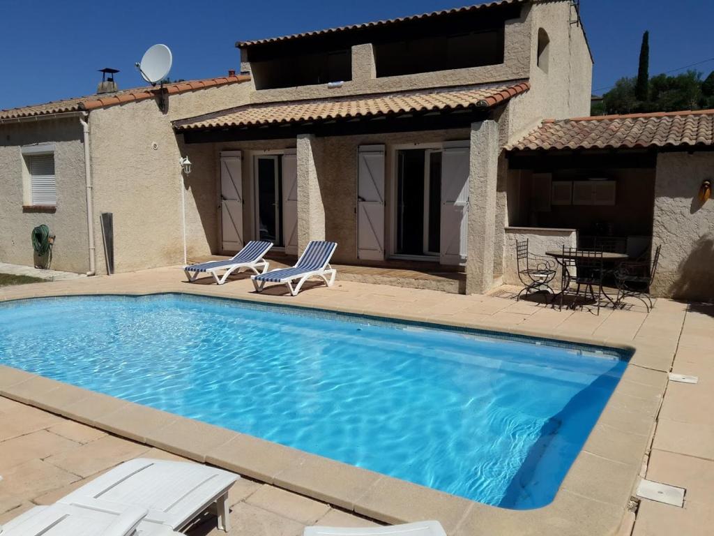 马里尼亚讷jolie villa avec piscine的一个带两把椅子的游泳池以及一座房子