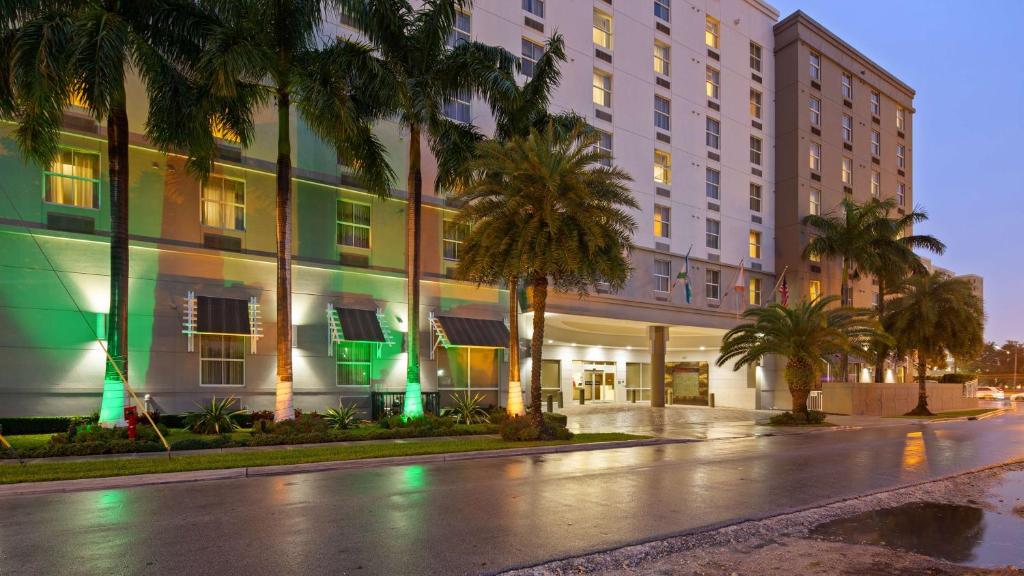 迈阿密Best Western Plus Miami Intl Airport Hotel & Suites Coral Gables的棕榈树建筑前的一条空街道