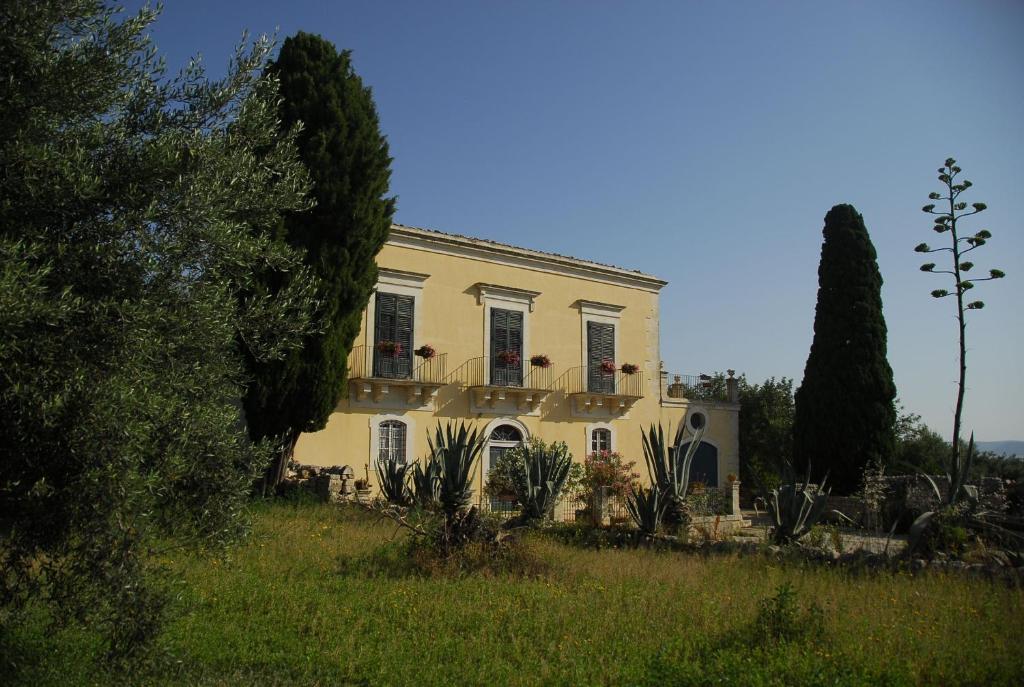 莫迪卡Agriturismo Baglio Calanchi的一座白色的房子,有两扇窗户,田野里种植着植物