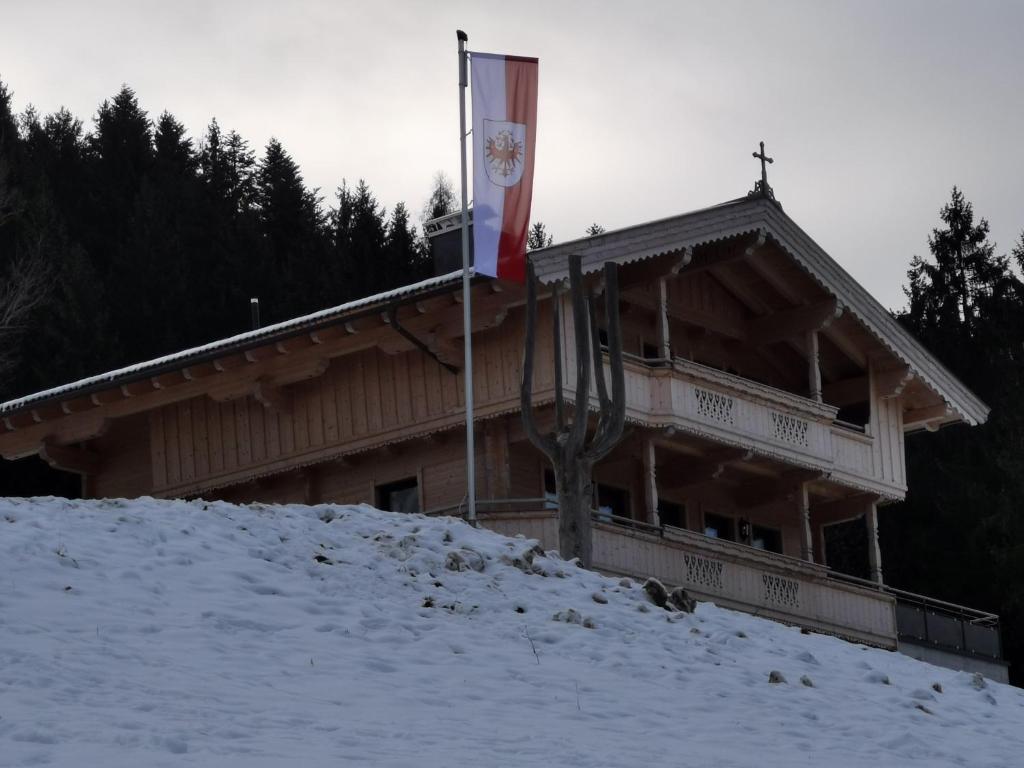 奥贝劳s' Riedlhof Zuhäusl的雪中带有旗帜的建筑