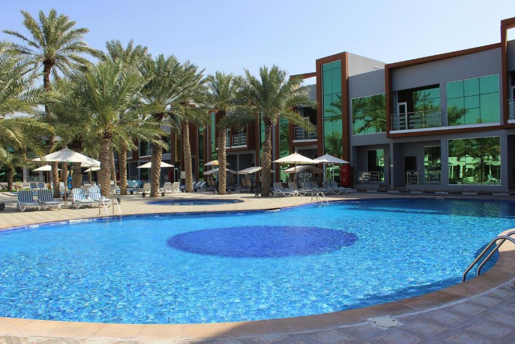 乌姆盖万Royal Residence Hotel Apartments的一座楼前棕榈树游泳池