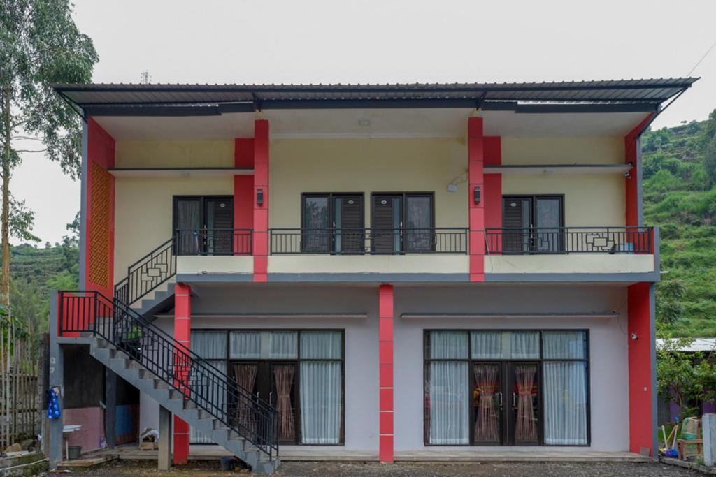沃诺索博RedDoorz @ Gerbang Dieng Plateau Area的拥有红色柱子和阳台的房子
