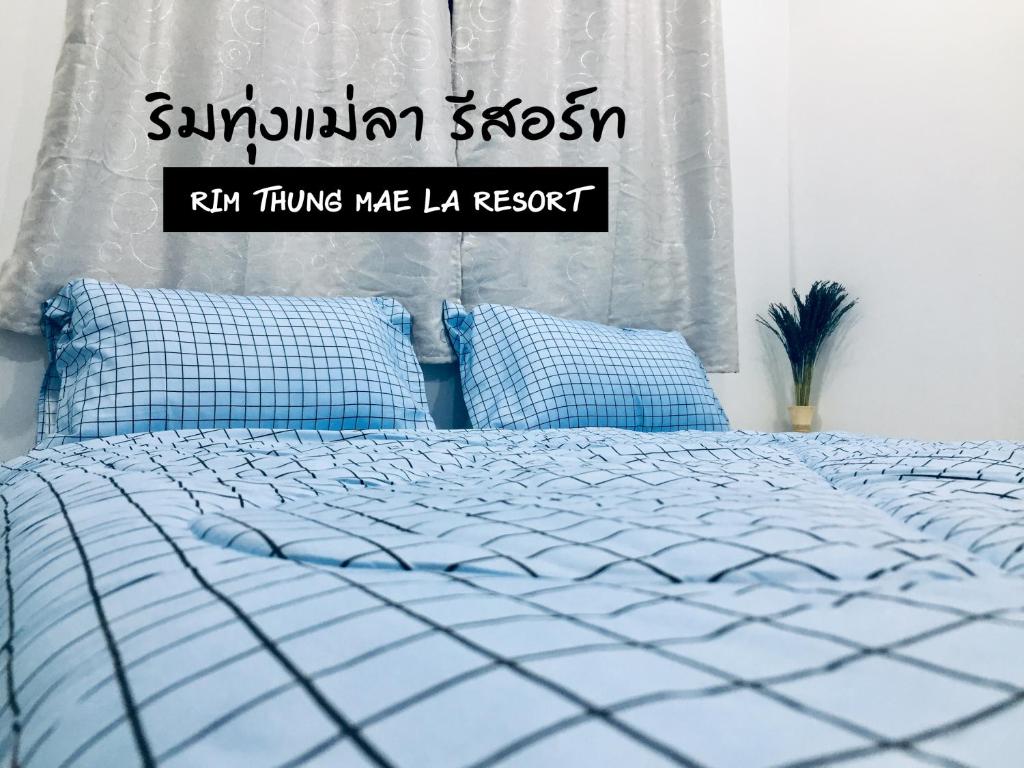 信武里府ริมทุ่งแม่ลา รีสอร์ท Rim-Thung-Mae-La-Resort的一间卧室配有一张带蓝色枕头的床和一扇窗户。