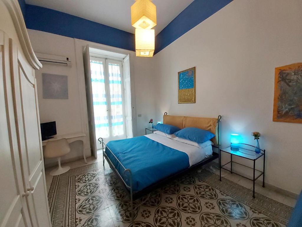 那不勒斯B&B Platamon的一间卧室配有一张带蓝色床单的床和一扇窗户。