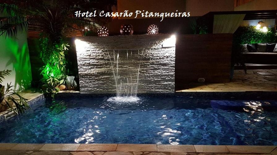 瓜鲁雅Hotel Casarão Pitangueiras的夜间后院的瀑布游泳池