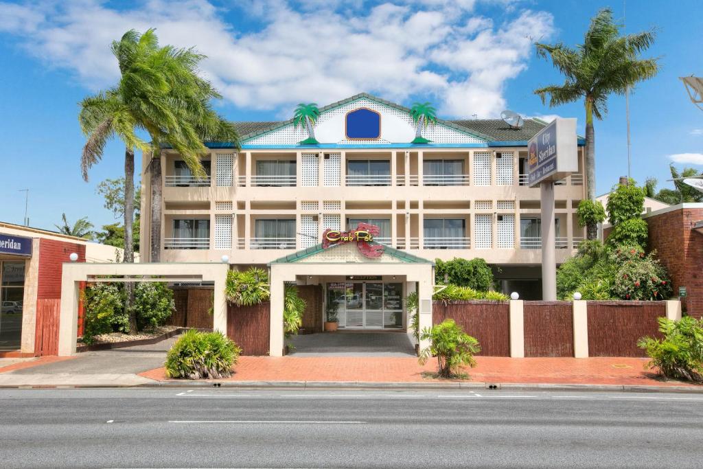 凯恩斯Cairns City Sheridan Motel的一条白色的大建筑,在街上种有棕榈树