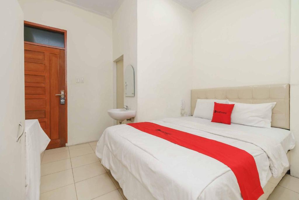 TarutungRedDoorz @ Haraito Tarutung的卧室配有一张大白色床和红色枕头