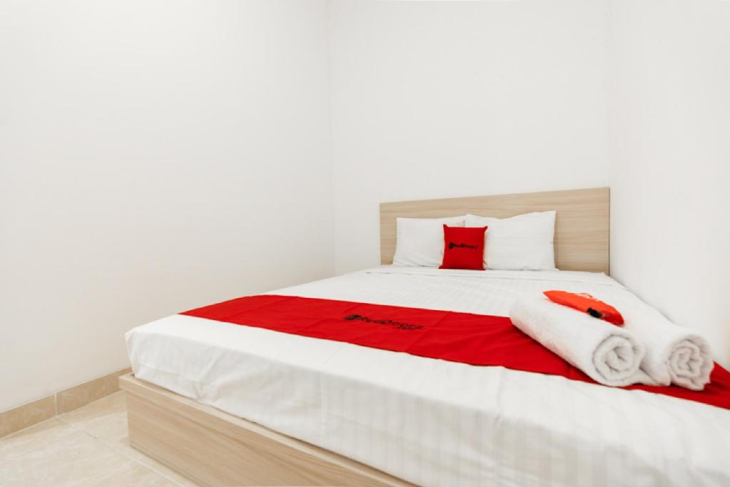 马卡萨RedDoorz @ Graha Cemerlang Maros的白色的床,上面有红色和白色的毛巾