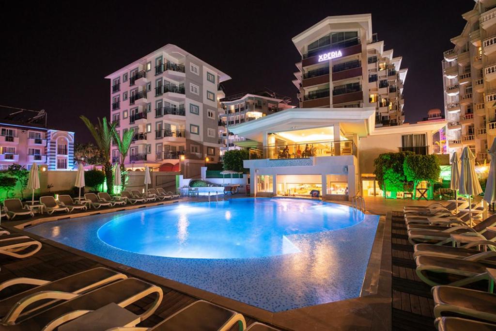 阿拉尼亚Xperia Saray Beach Hotel的一座带椅子的大型游泳池,晚上则在大楼里