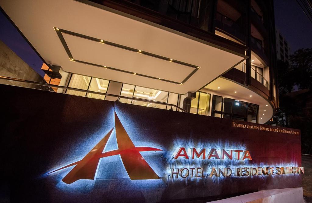 曼谷Amanta Hotel & Residence Sathorn的夜间在建筑物前的标志