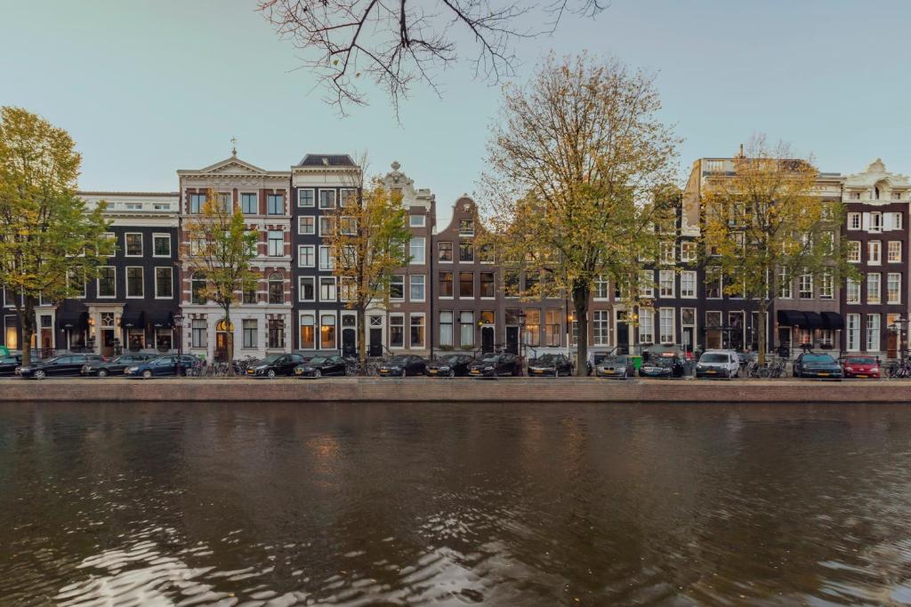 阿姆斯特丹The Pavilions Amsterdam, The Toren的河边一排有汽车的建筑物
