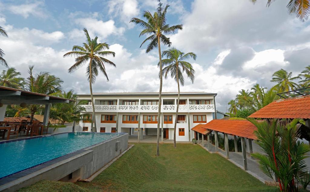 乌斯维塔克伊亚瓦海滩精品酒店的一座带游泳池和棕榈树的建筑