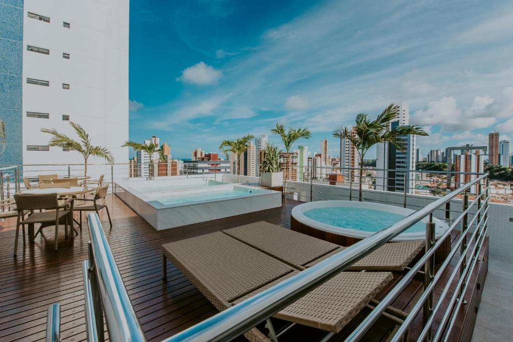 若昂佩索阿Guest Manaíra Apart Hotel的阳台设有游泳池、桌子和椅子。